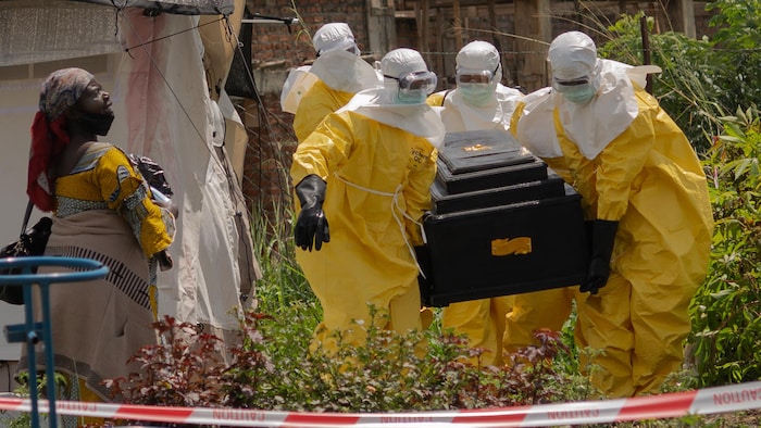 Les travailleurs humanitaires en tenue de protection transportent le cercueil.