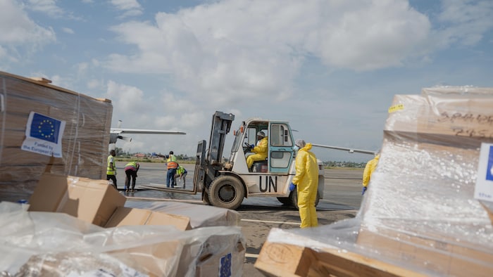 Des ouvriers déchargent du matériel médical à leur arrivée à l'aéroport national de Bunia, au Congo.