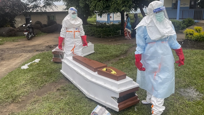 Du personnel médical portant un équipement de protection individuelle (EPI) près du cercueil d'un patient décédé des suites d'Ebola, dans un hôpital de Rwampara, le 21 mai 2026. 