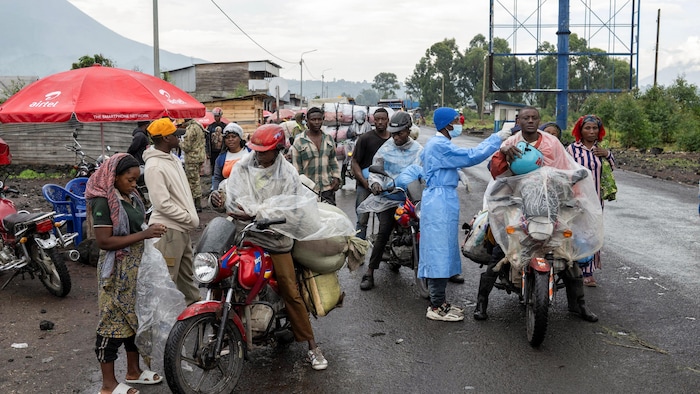 Un homme en motocyclette à côté d'un travailleur de la santé avec de l'équipement de protection. 