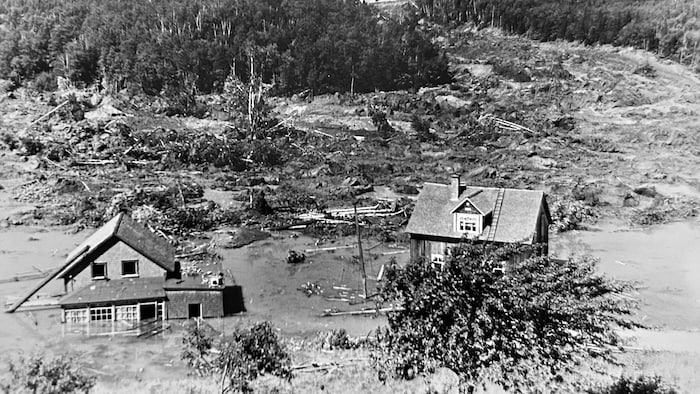 Des maisons en partie submergées reposent dans la rivière Rimouski. Le parcours de l'éboulis est visible. De nombreux arbres ont été arrachés.