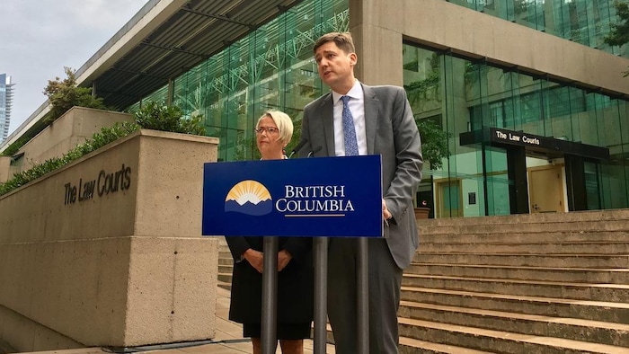 Judy Darcy et David Eby, deux politiciens provinciaux de la Colombie-Britannique devant un lutrin à l'extérieur de la Cour à Vancouver. 