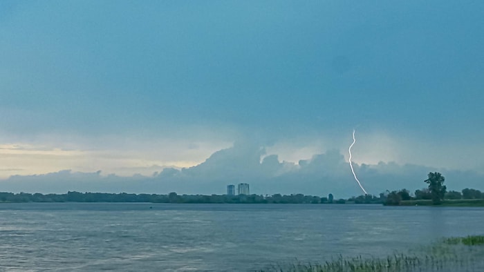 Un éclair vu au loin, au bout d'une étendue d'eau.