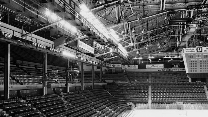 Vue intérieure du Forum de Montréal où on voit une partie du plafond, de la patinoire et des gradins au travers desquels sont installées des caméras de télévision sur des plateformes pour la télédiffusion des parties de hockey.