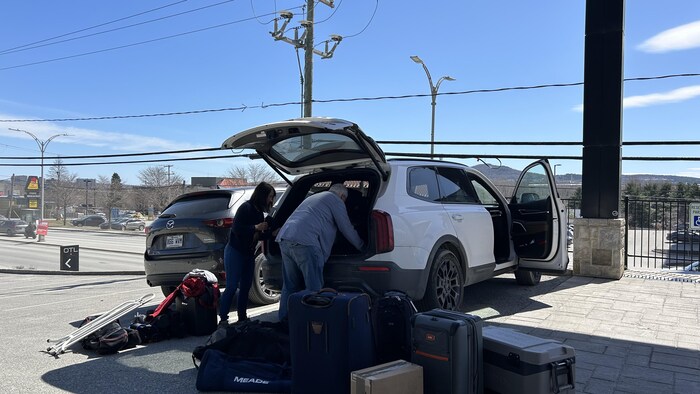 Evan et Paula placent leurs bagages dans leur voiture. 