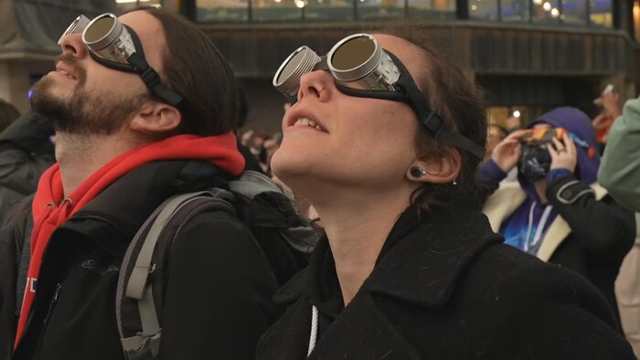 Deux observateurs la tête en l'air et avec des lunettes métalliques.