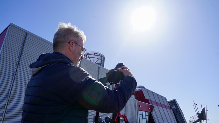 Un homme photographie l'éclipse avec son appareil photo. 
