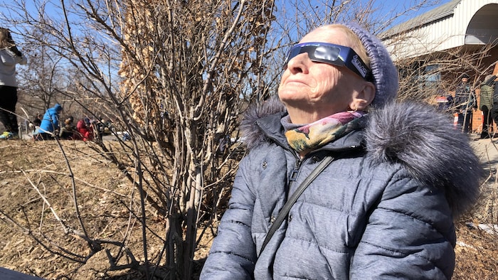 Une dame qui porte des lunettes de protection regarde vers le ciel. 