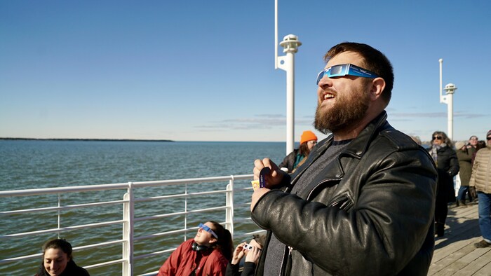 Un homme observe l'éclipse avec ses lunettes solaires. 
