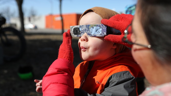 Un enfant porte des lunettes pour l'éclipse.