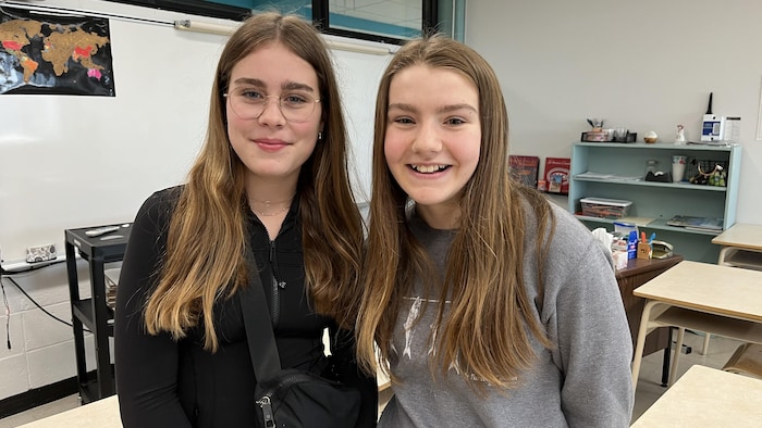 Alice Cyr et Elodie Arseneau sont dans une classe et sourient à la caméra.