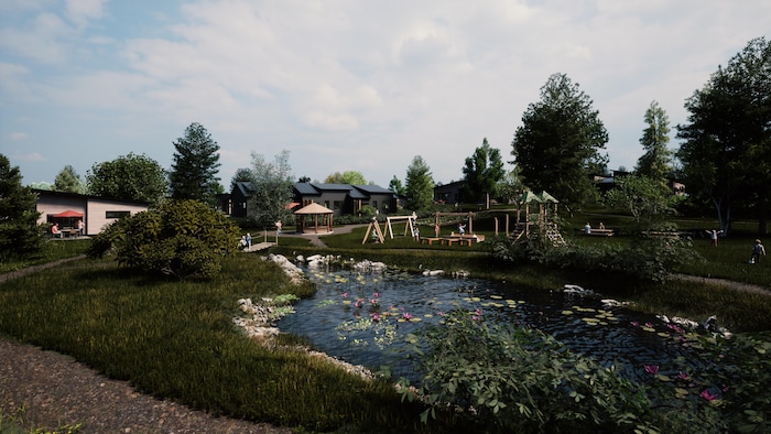 Un petit étang entouré de verdure et d'un parc pour enfants derrière de petites maisons.