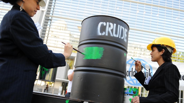 Manifestantes pintan un bidón de petróleo con pintura verde.
