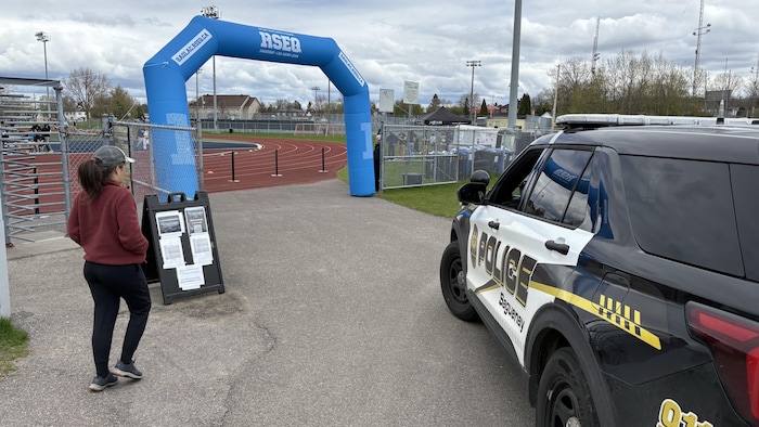 Un véhicule de police près d'un terrain sportif.