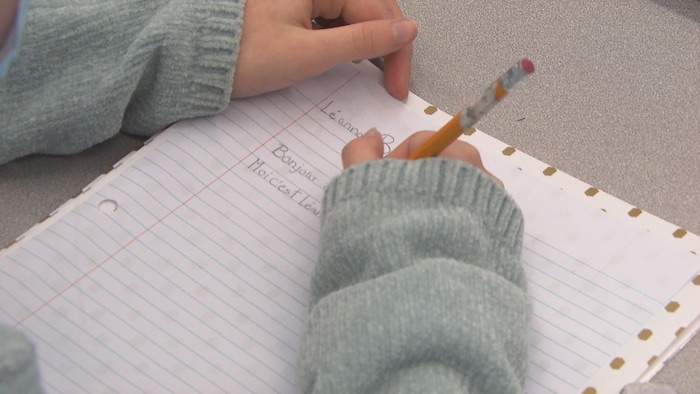 Une jeune fille écrit sur une feuille de papier.