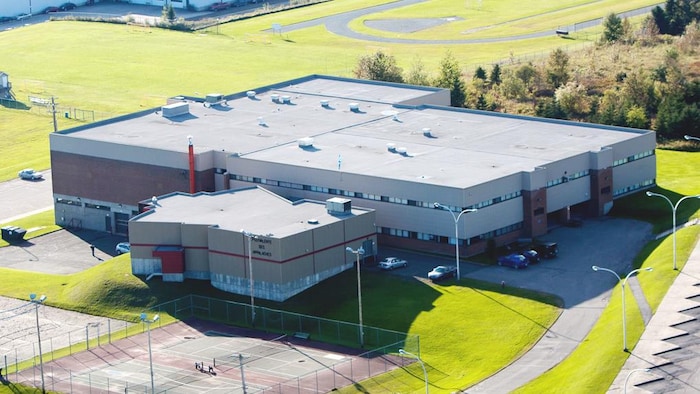 Une petite école secondaire vue de haut. Elle est entourée de gazon vert.