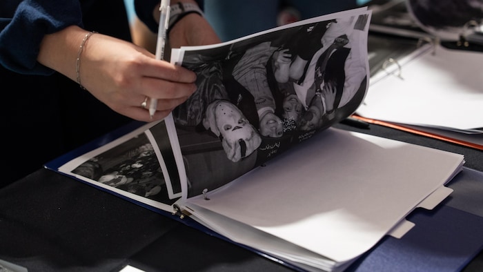 Une personne regarde des photos en noir et blanc dans un classeur, à l'École Émilie-Tremblay.