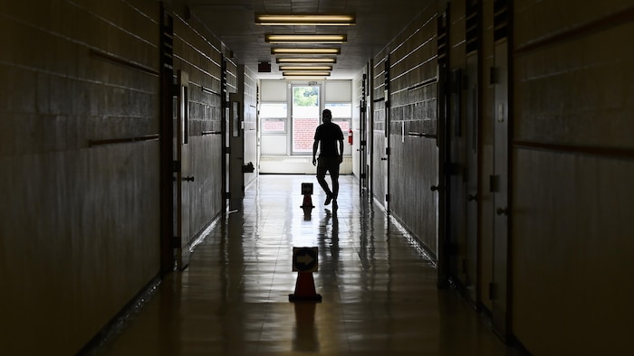 Un enseignant marche dans le couloir vide d'une école.