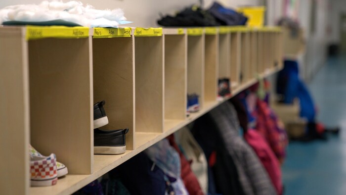Des chaussures et des manteaux sont rangés le long du mur dans le couloir d'une école.