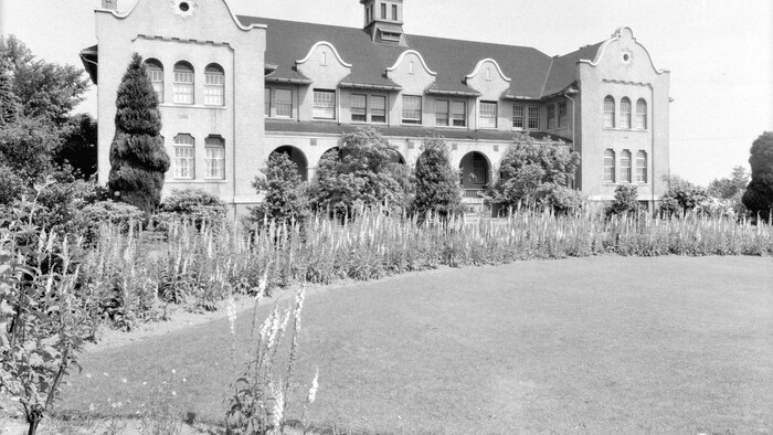 Une photo en noir et blanc d'un bâtiment en briques de deux étages.
