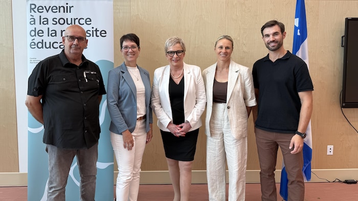 Cinq personnes sourient à la caméra pour une photo de groupe.