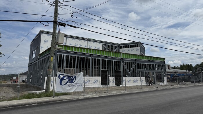 Un bâtiment en construction derrière des clôtures de sécurité.