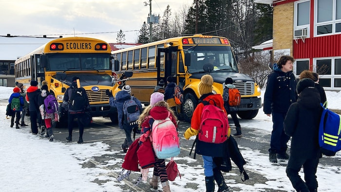 Des enfants marchent vers l'autobus scolaire.