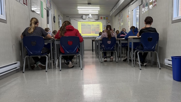 Une salle de classe a été recréé dans une roulotte, avec tableau, tables et chaises et des affiches sur les murs.