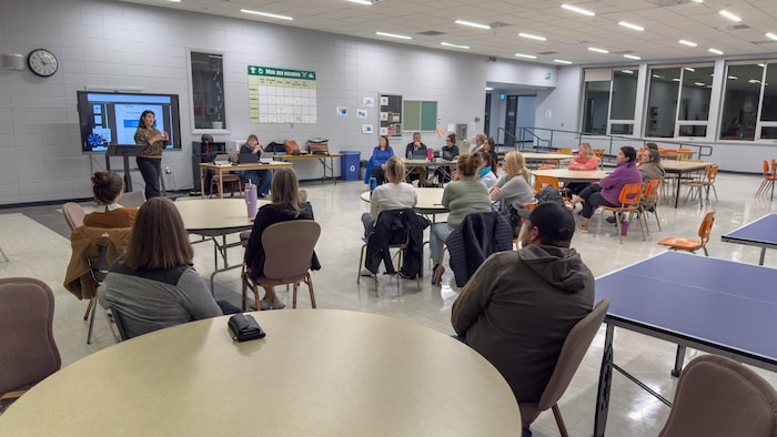 Des gens assistent à une rencontre dans une cafétéria d'école