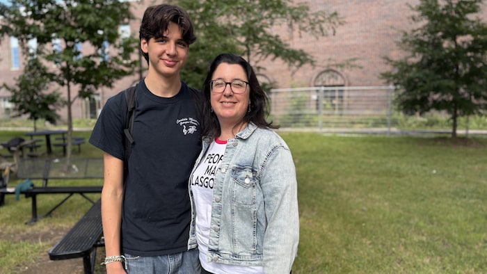 Un fils et sa mère posent devant une école secondaire.