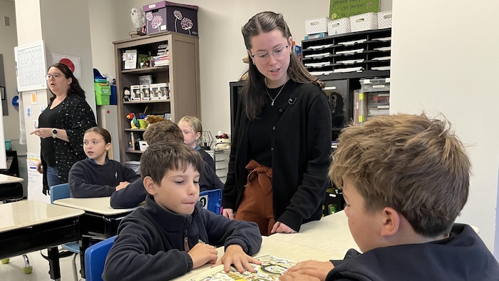 Madame Béatrice aide des élèves dans la classe de Madame Martine.