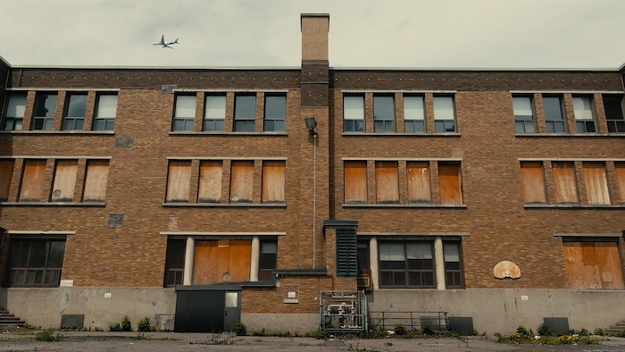 Une école vu de l'extérieur avec plusieurs fenêtres placardées. 