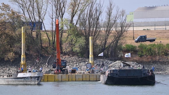 Vue sur une barge chargée de rochers et d'ouvriers au travail.