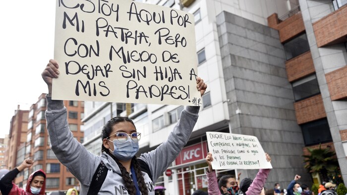 Una manifestante sostiene una pancarta que dice "Estoy aquí por mi país, pero tengo miedo de dejar a mis padres sin una hija" durante una protesta antigubernamental el 4 de mayo de 2021 en Bogotá, Colombia. Las protestas se convirtieron en un clamor nacional contra el aumento de la pobreza, la desigualdad y el desempleo agravados por la pandemia. 