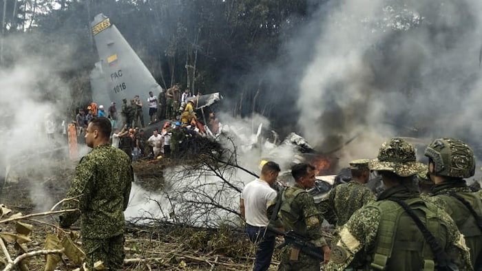 Des soldats et des secouristes près d'un Hercules de l'armée de l'air dégageant une épaisse fumée après que l'appareil s'est écrasé au décollage à Puerto Leguizamo, en Colombie, près de la frontière sud avec l'Équateur, le 23 mars 2026.