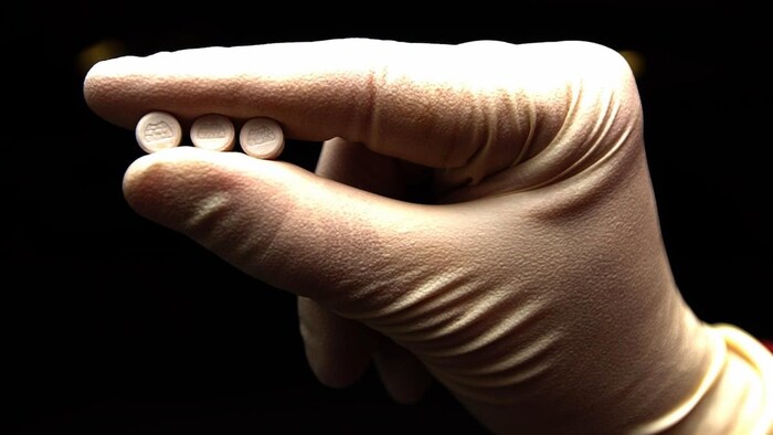 Une main tient trois cachets de MDMA. 