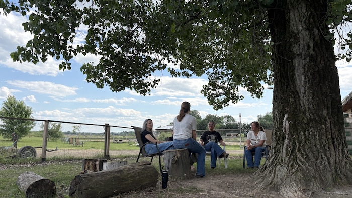 Les cowgirls sont assises à l’ombre d’un arbre.
