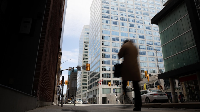 Un fonctionnaire marche devant un édifice fédéral du centre-ville d'Ottawa.
