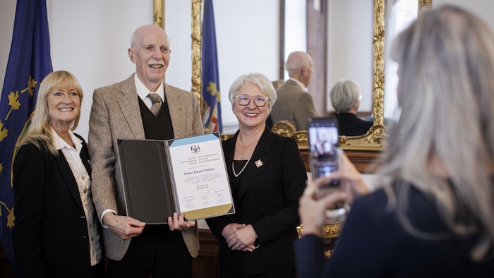 Edith Dumont remet un prix à des personnes.