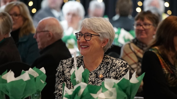 Edith Dumont assise à une table, toute souriante.