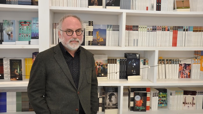 Portrait d'Antoine Tanguay devant une bibliothèque remplie de livres.