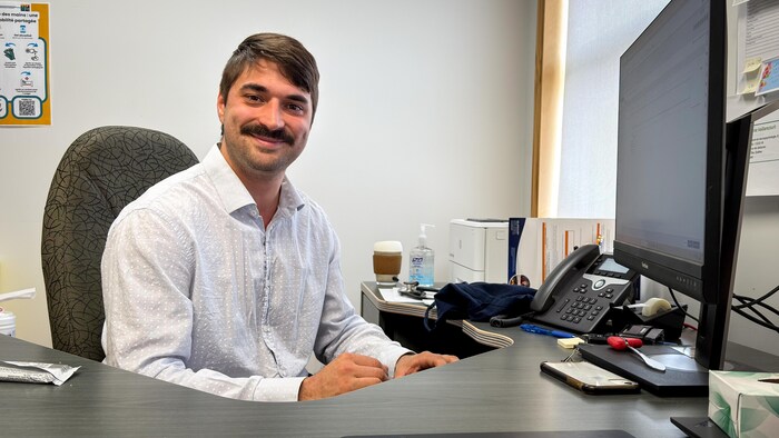 Un médecin moustachu devant son écran, dans un bureau. 