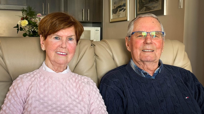 Un homme et une femme âgés assis côte à côte sur un divan.