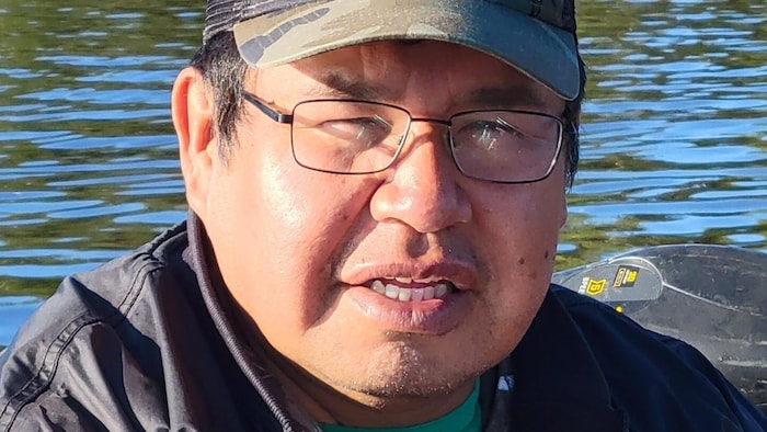 Edouard Brazeau pose pour la caméra, un lac en arrière-plan.