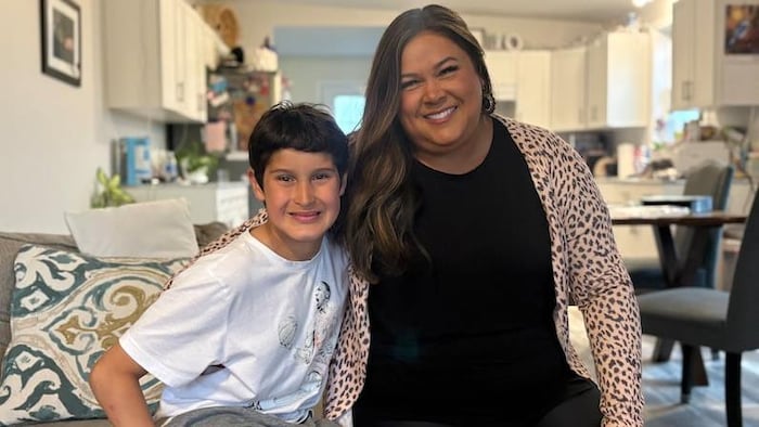 Une mère et son fils souriant dans le salon d'une maison. 