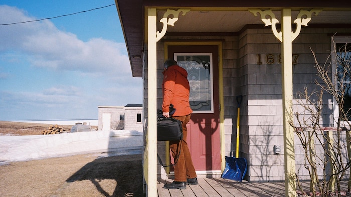 Une personne devant la porte de sa maison.