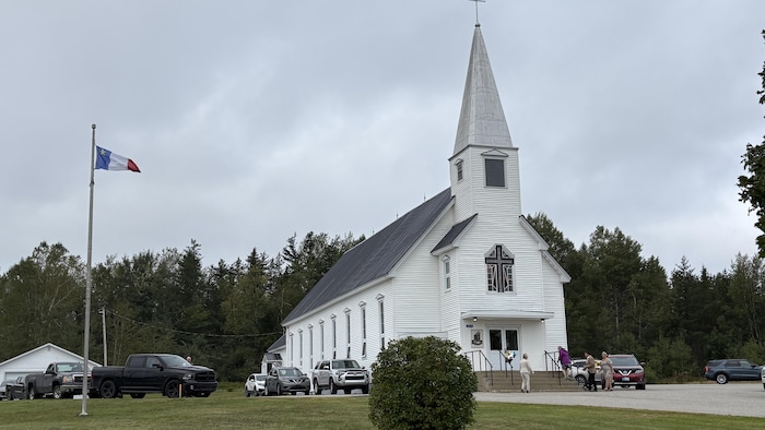 L'église de l'Ascension avec un drapeau acadien à ses côtés.