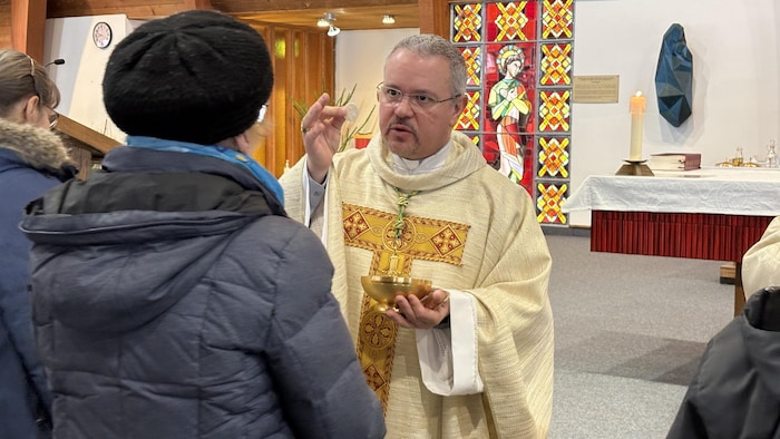L'évêque offre la communion à une fidèle dans le Sanctuaire Sainto-Pérégrin de Québec.