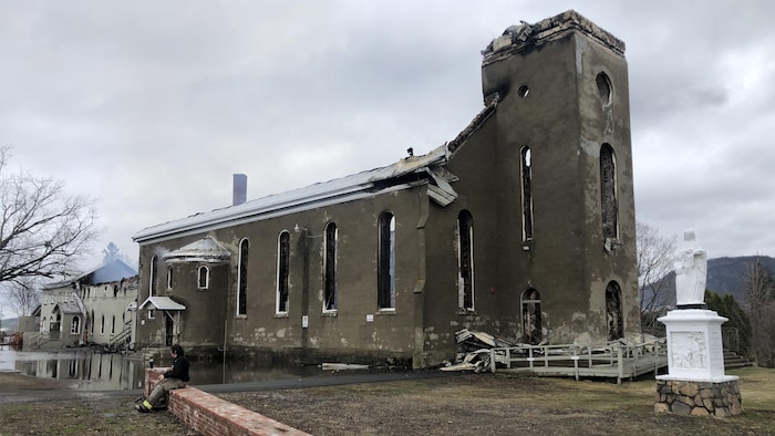 Un pompier est assis devant la structure calcinée de l'église, le 27 avril 2021.