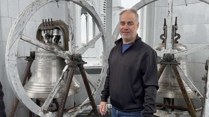 Le marguillier Erik Heppell devant les cloches d'une église.